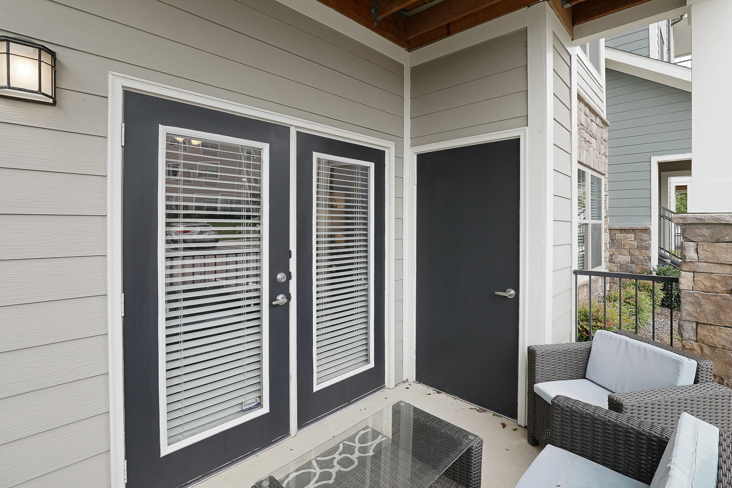 a front porch with two chairs and a glass table