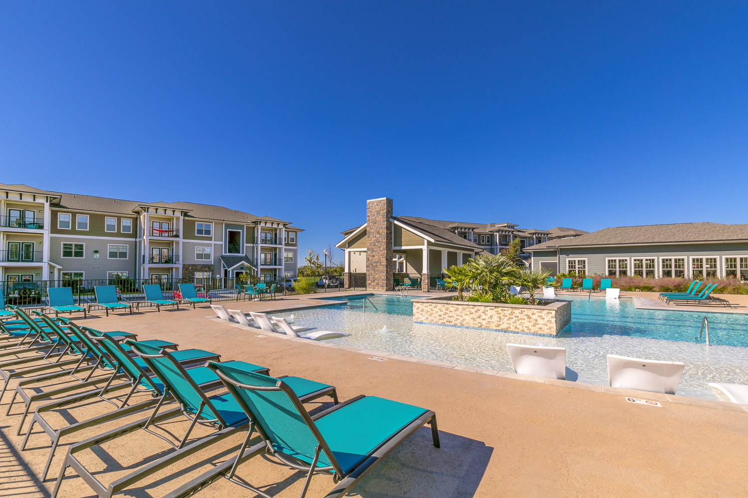 a swimming pool with blue chairs and a building in the background