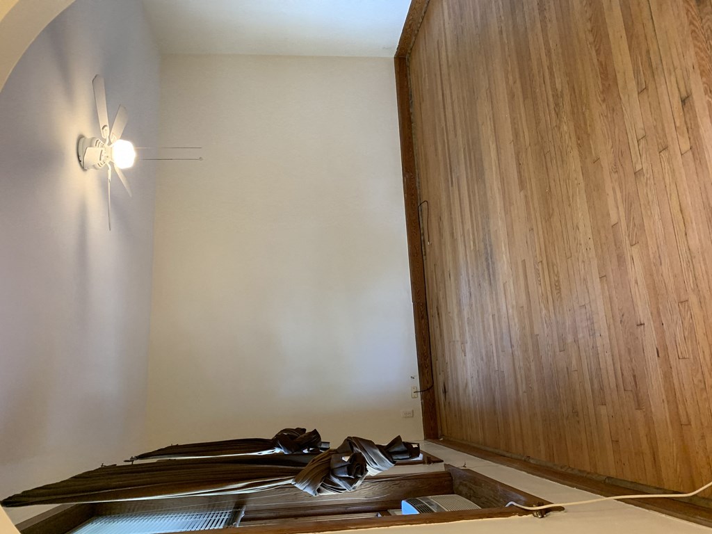 an empty room with wooden floors and a ceiling fan