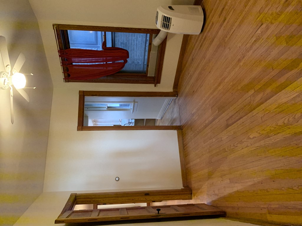 an empty living room with a hard wood floor and a window