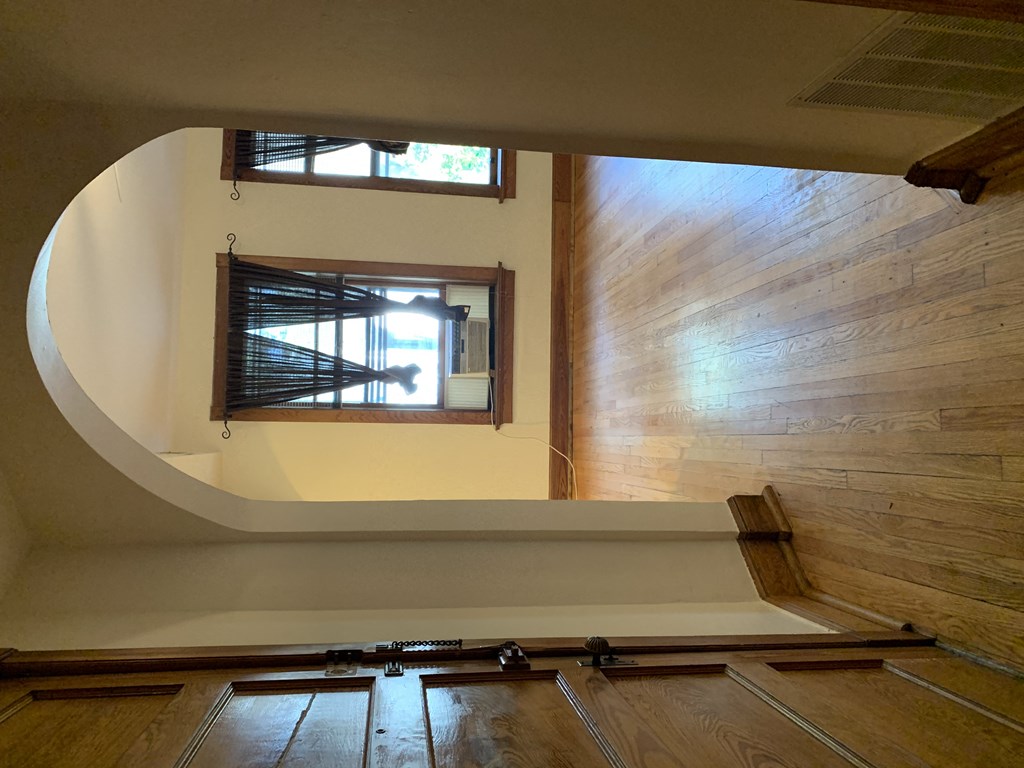 an empty living room with wood floors and a window