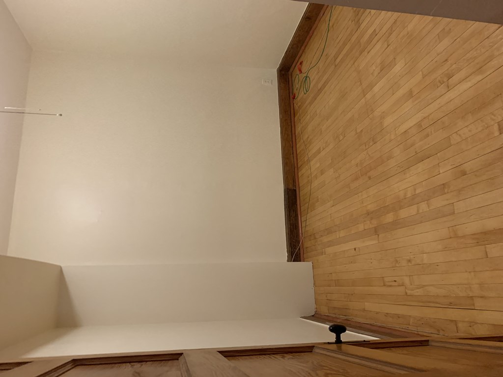 an empty room with wooden floors and white walls