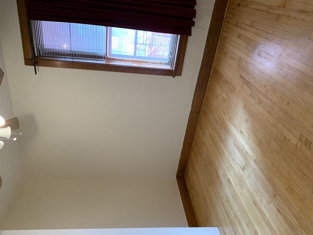 an empty living room with wood floors and a window