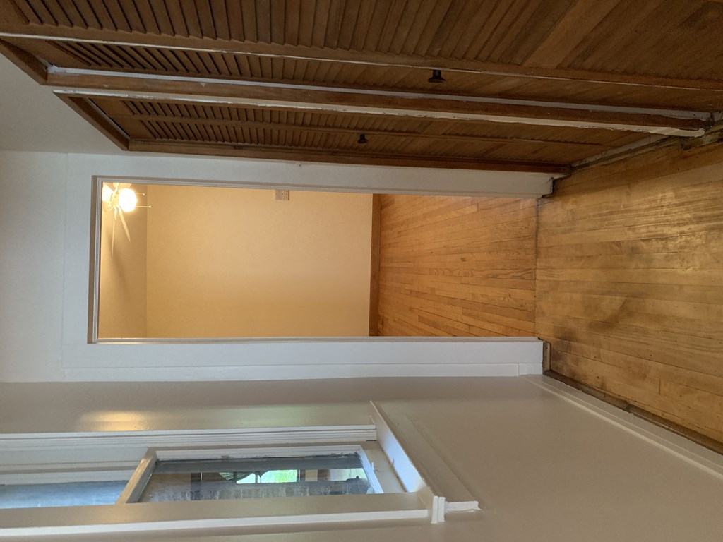 a hallway with a closet and a window and a wooden floor