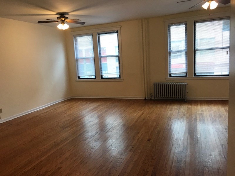 an empty living room with wood floors and a ceiling fan