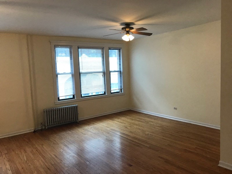 an empty living room with a ceiling fan and a window