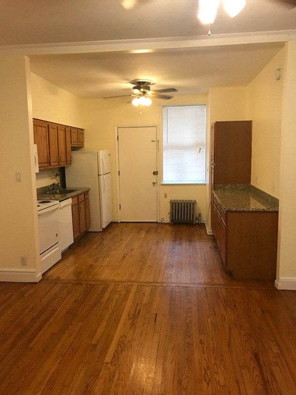 an empty kitchen with wood floors and a ceiling fan