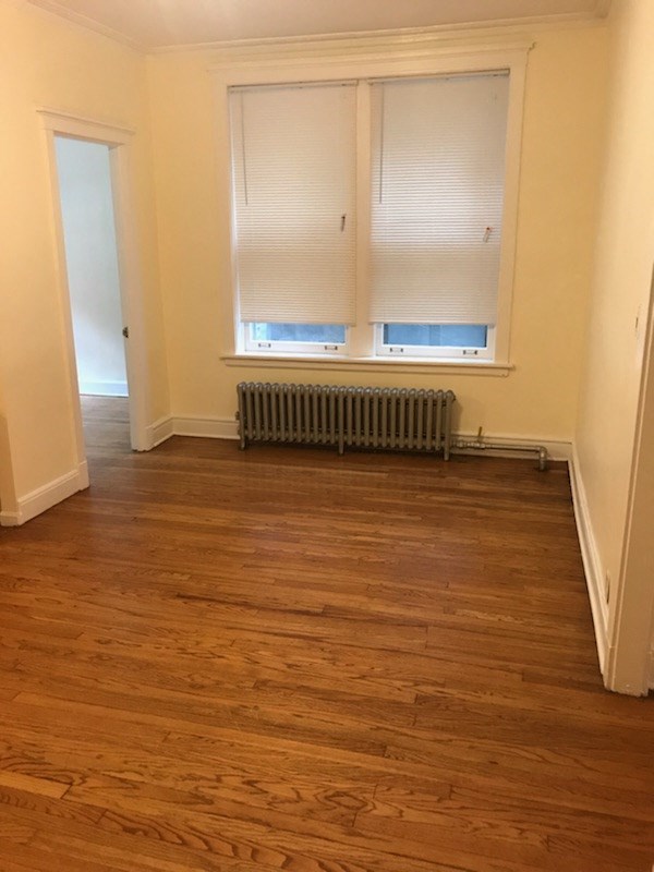 an empty room with a wood floor and a radiator