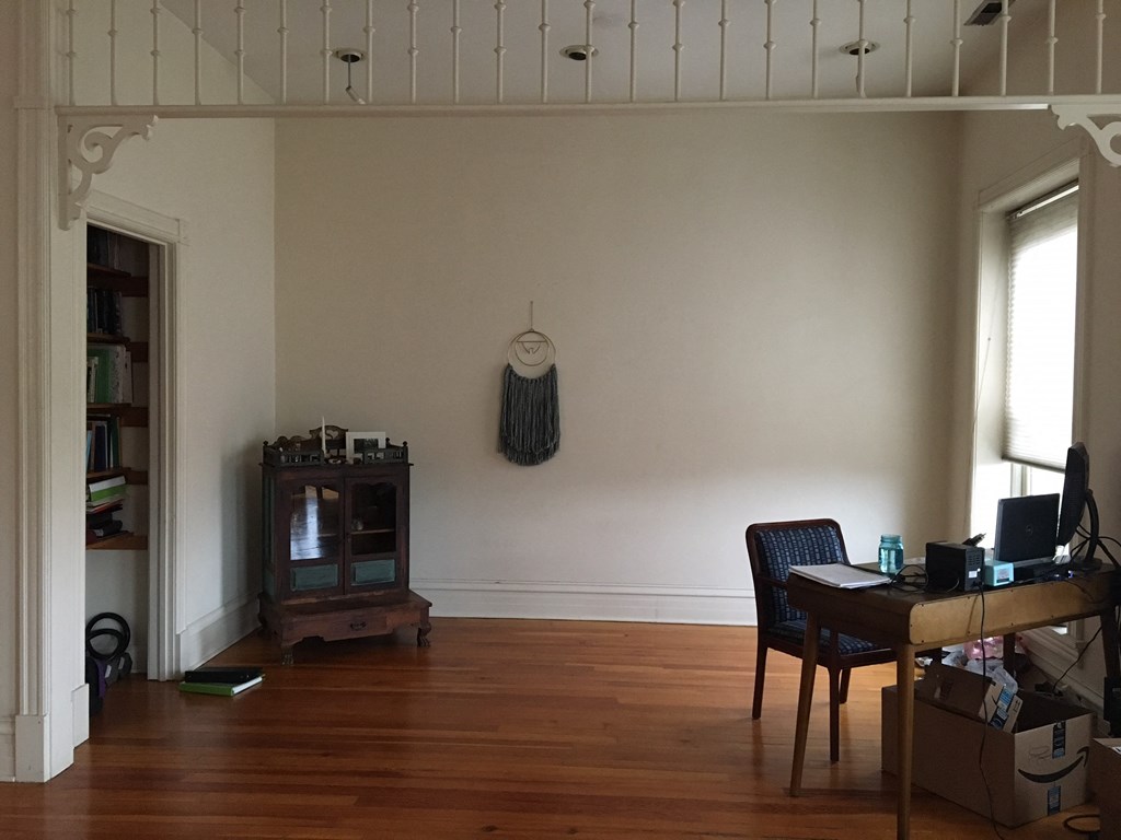a living room with a wooden floor and a desk and a tv