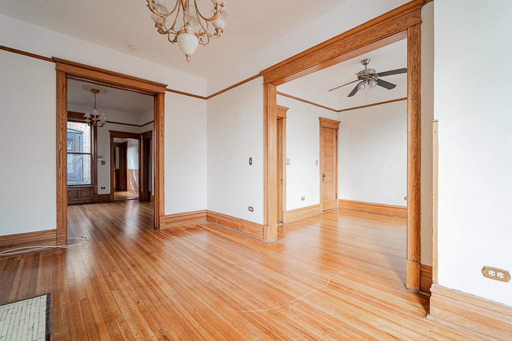 an empty living room with wood floors and a ceiling fan