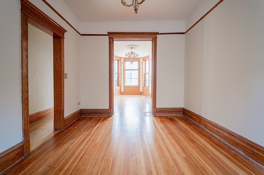 a empty living room with wood floors and a door to a hallway