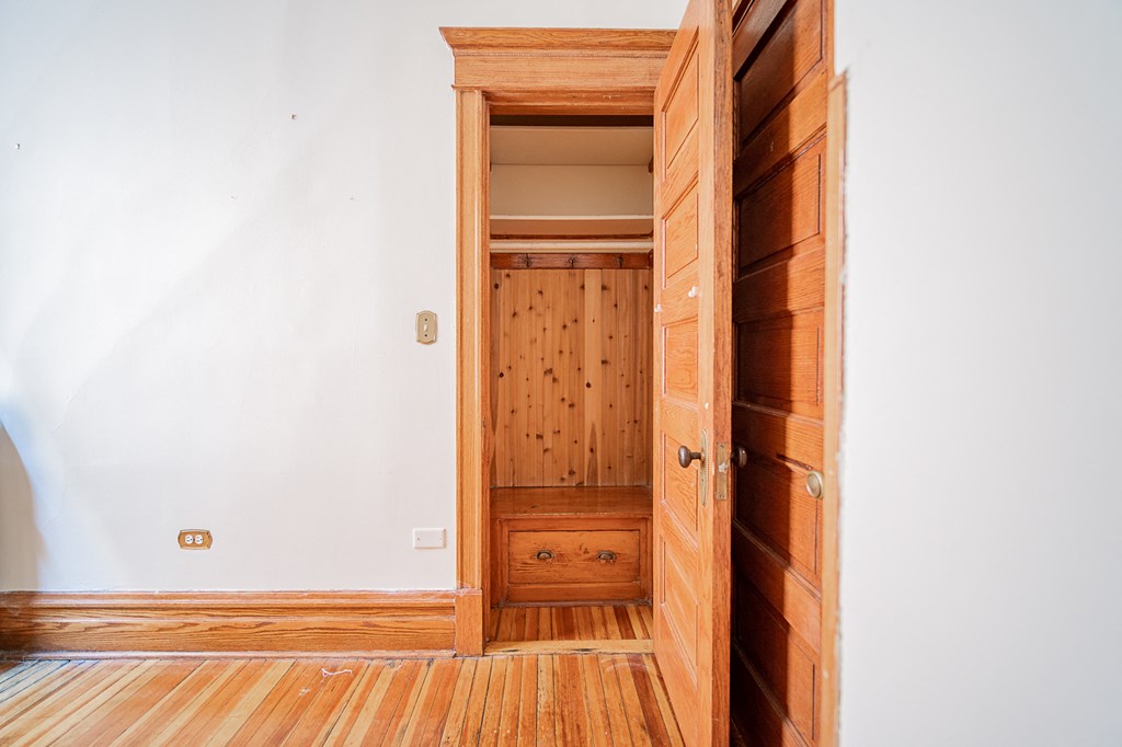 a wooden door is open to a room with wood floors and a closet