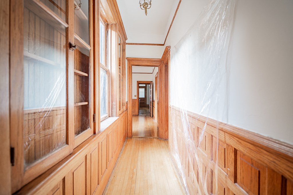 a hallway with wood paneling and windows and a wooden floor