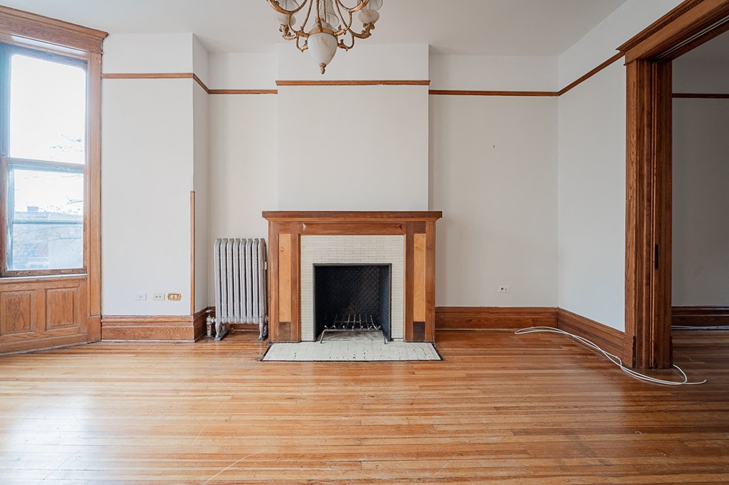 an empty living room with a fireplace and wooden floors