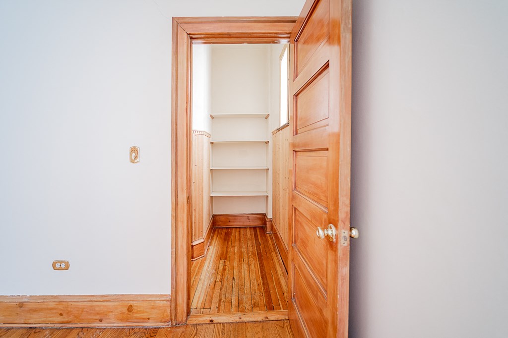a room with a wooden door and a closet with shelves