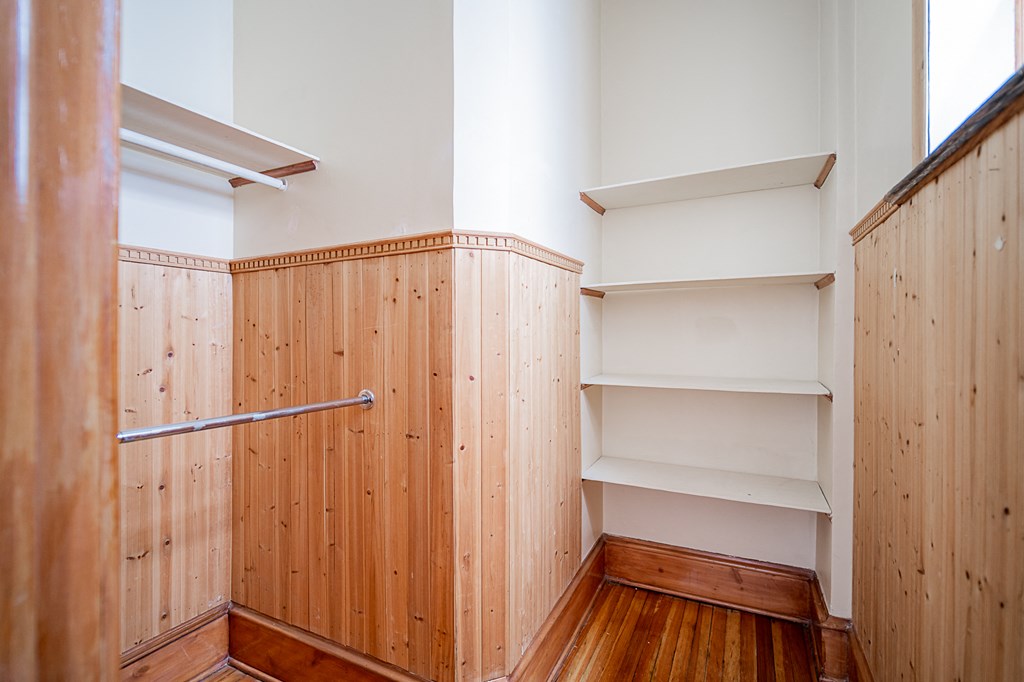 a closet with wood paneling and white walls and shelves