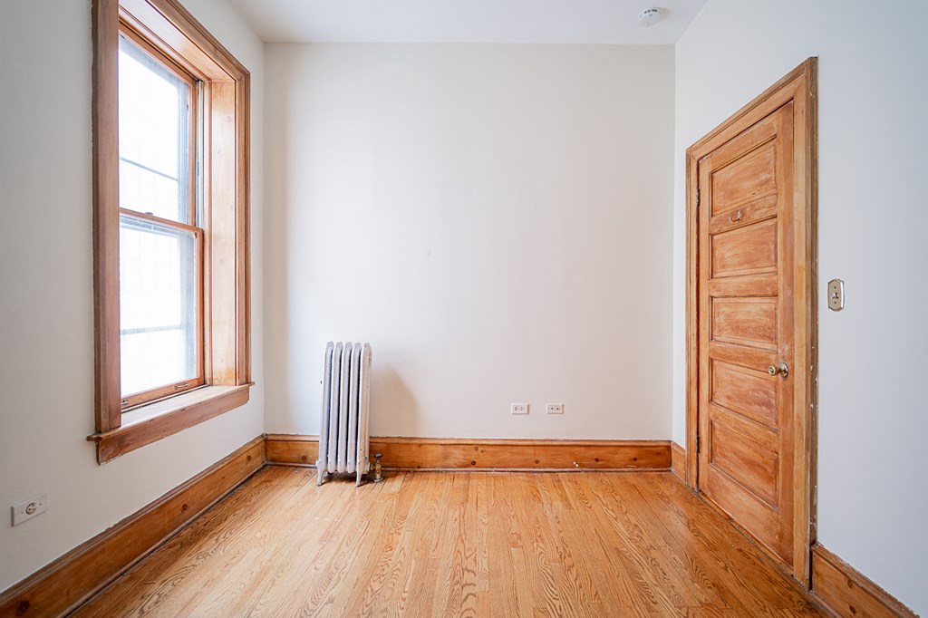 a room with a wood floor and a window and a wooden door