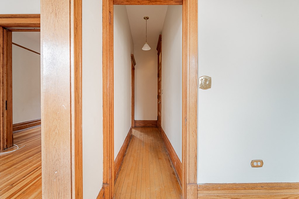 an empty hallway with wood floors and white walls