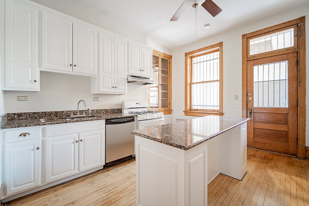 a kitchen with white cabinets and a marble counter top