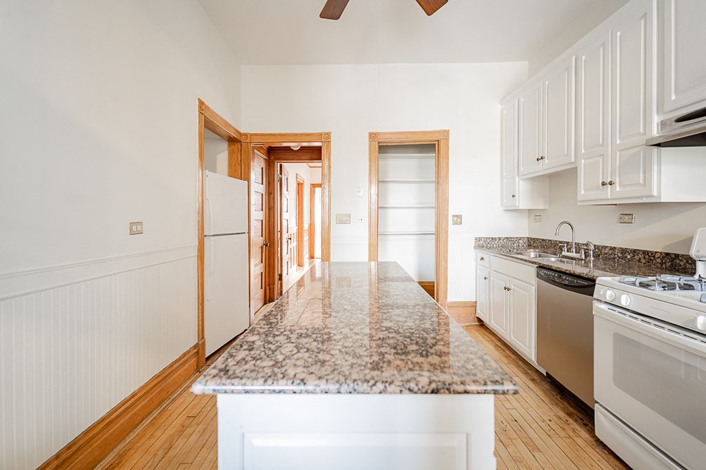 a kitchen with white cabinets and a granite counter top