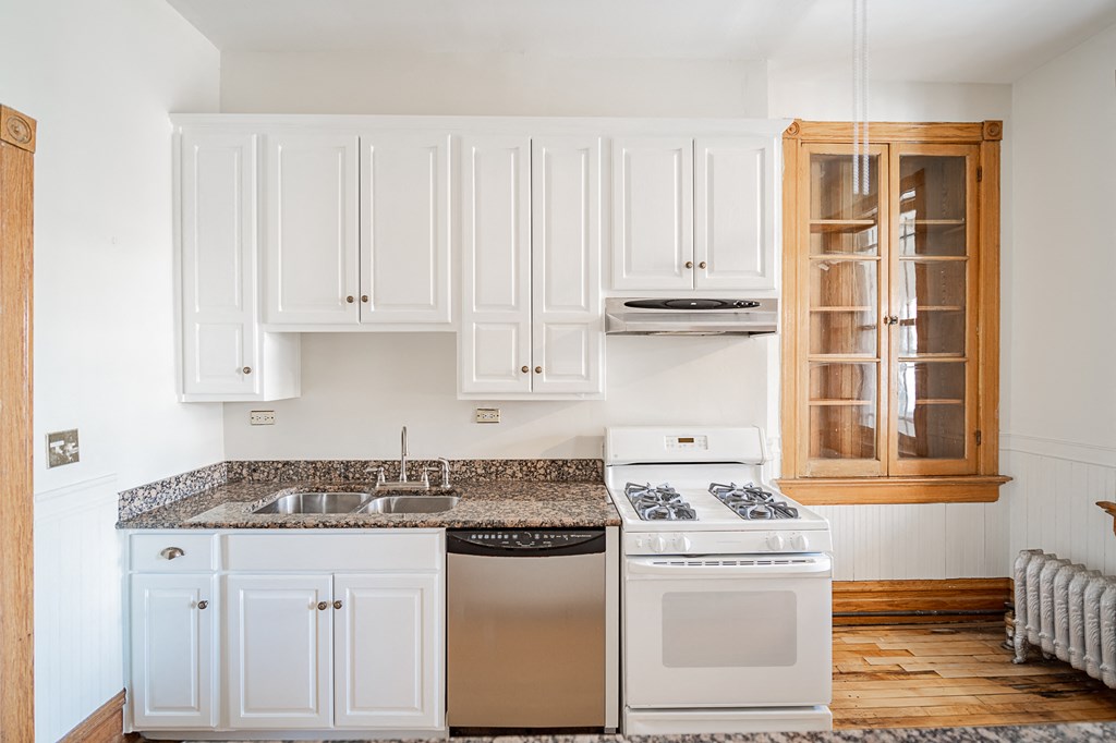 a kitchen with white cabinets and white appliances and granite counter tops
