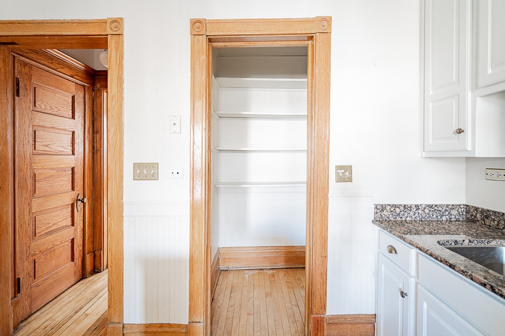 an empty pantry in a kitchen with white cabinets and a wooden door