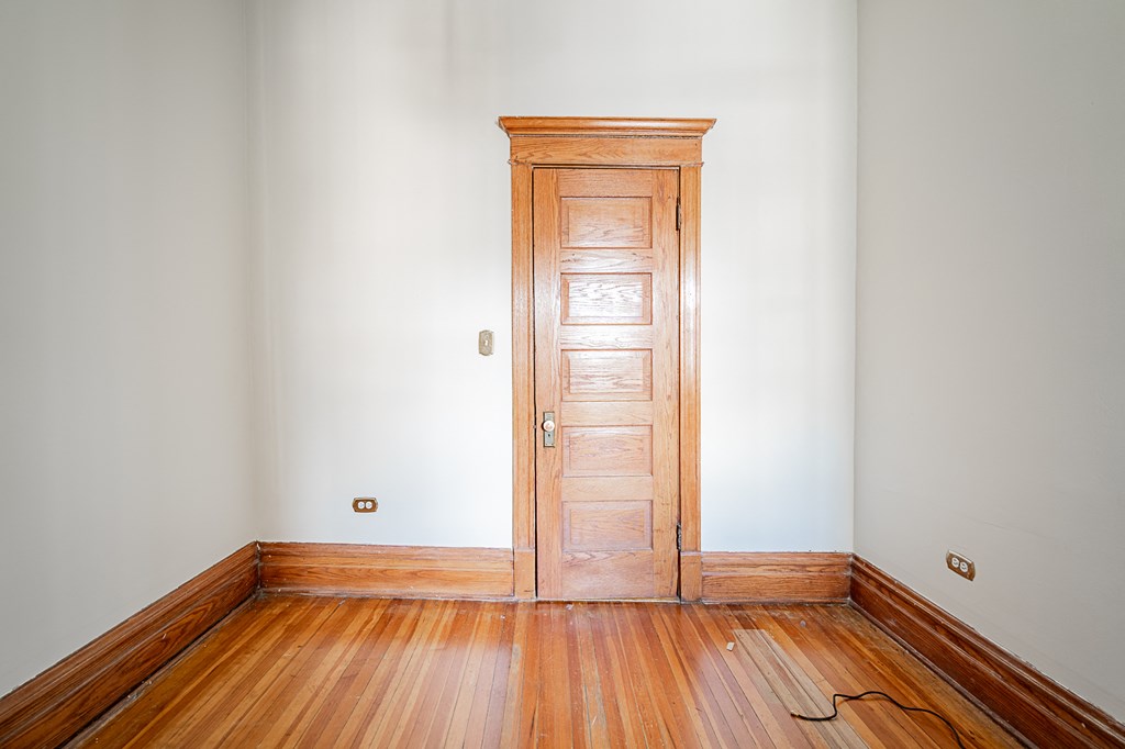 a wooden door in a white room with wooden floors