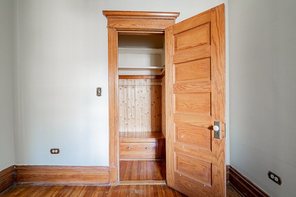 a room with a wooden door open to a closet and a staircase