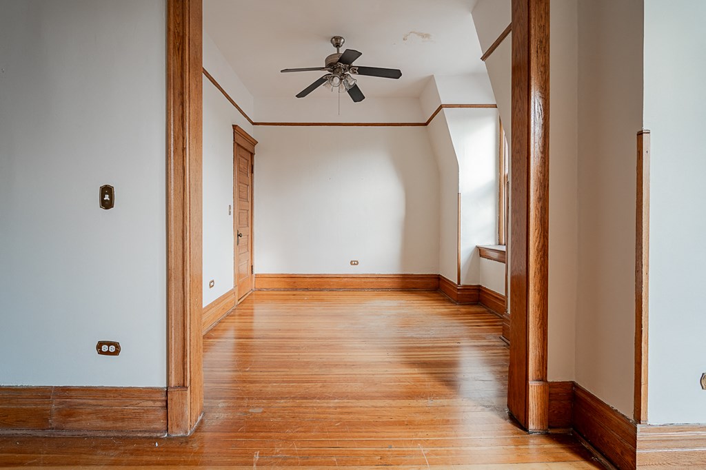 a empty room with wooden floors and a ceiling fan