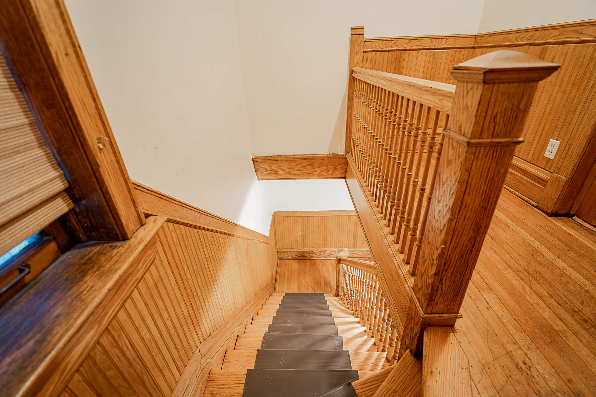 a view down the stairs of a house with wooden floors