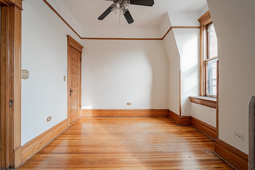 an empty room with wooden floors and a ceiling fan