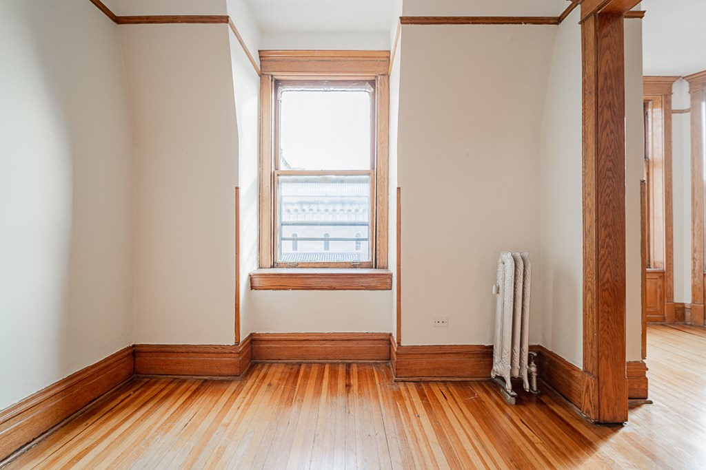 an empty room with wood floors and a window
