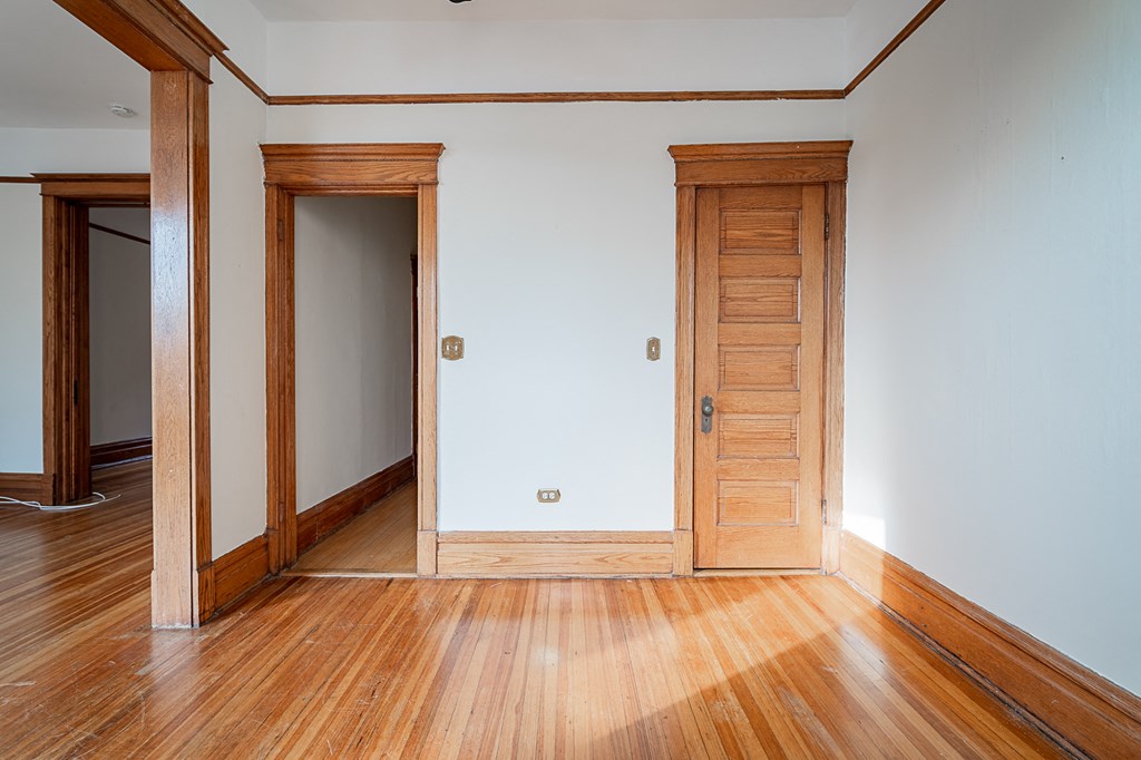 a living room with wooden floors and a white wall and wooden doors