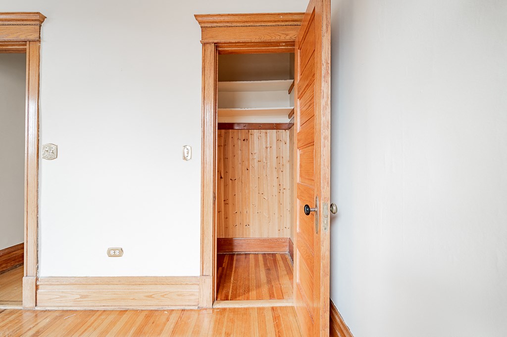 an empty room with a wooden door open to a closet