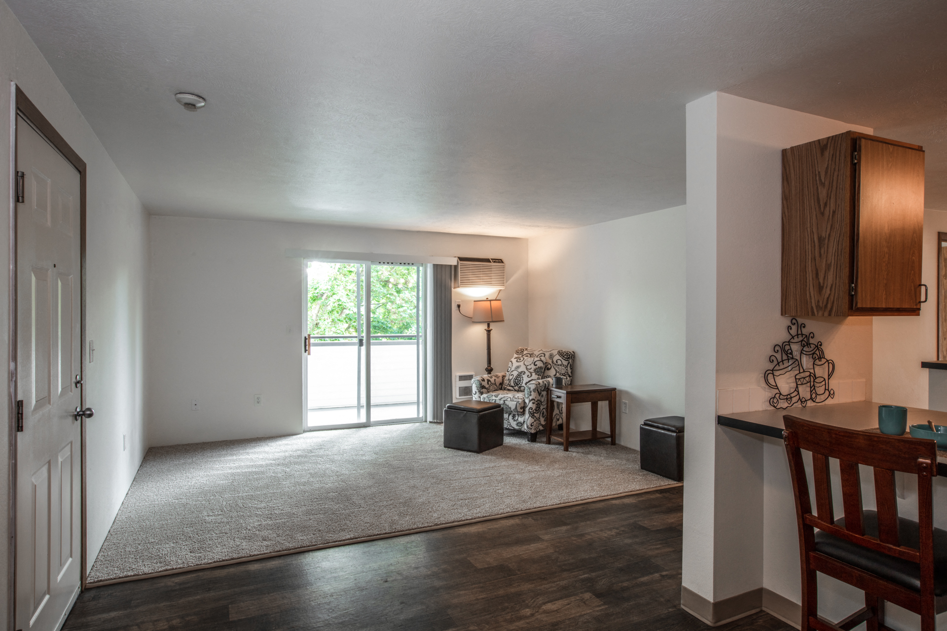 a living room with a rug and a door to a balcony