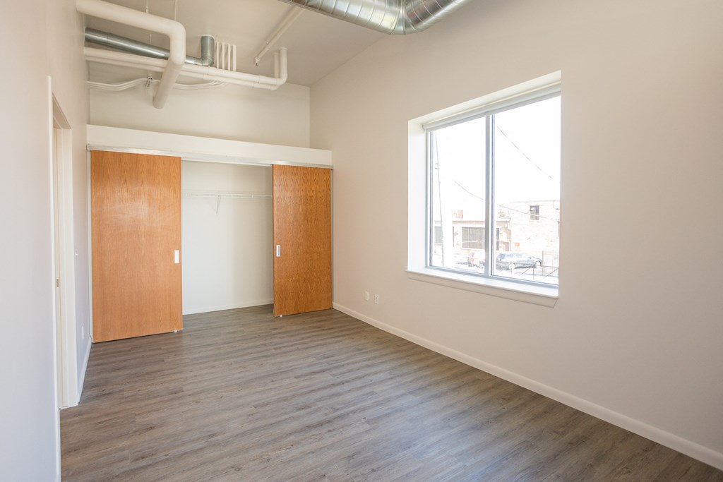 A room with wooden floors and a window overlooking a cityscape.