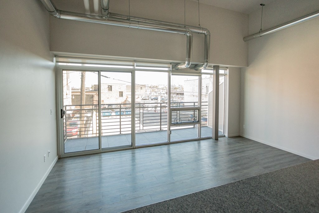 A room with a view of a parking lot through the glass doors.