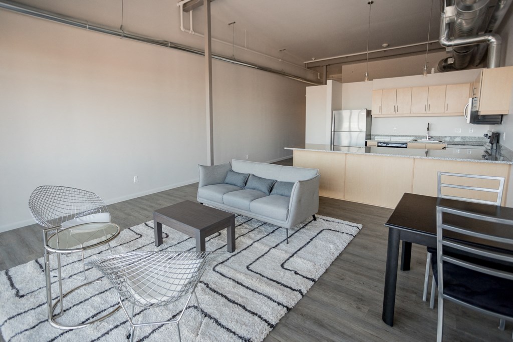 A modern living room with a kitchen in the background.