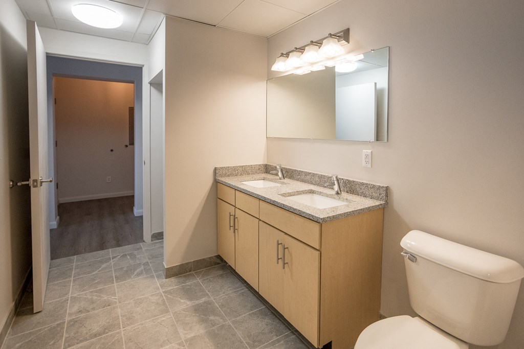 A bathroom with a sink, toilet, and mirror.
