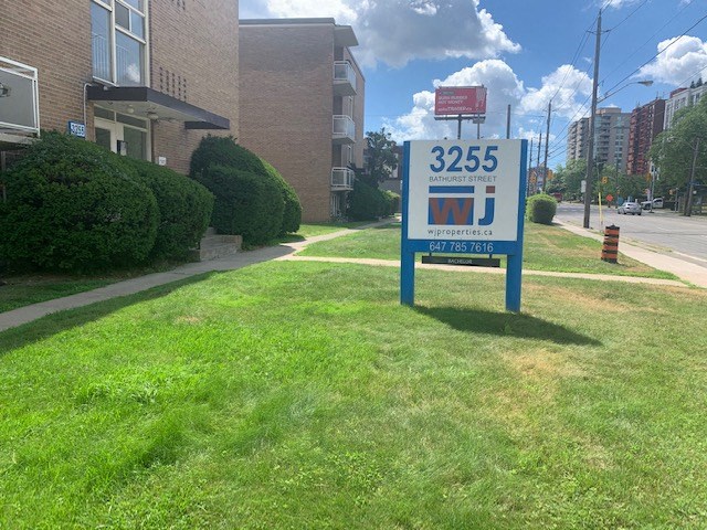 a gas station sign in the grass in front of a building