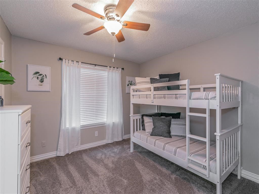 Bedroom with large window and ceiling fan in Riata Park Apartment