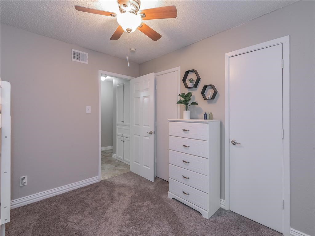 Bedroom with large window and ceiling fan in Riata Park Apartment