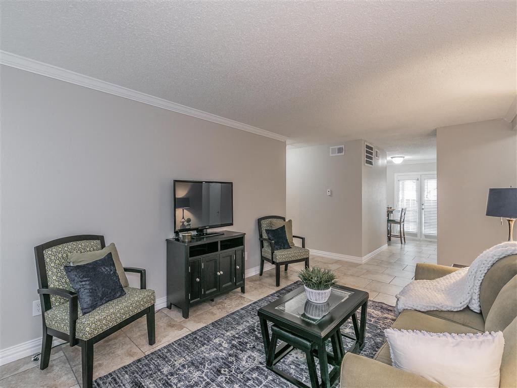 Open-concept living room with neutral tones and tile floors at Riata Park Apartments