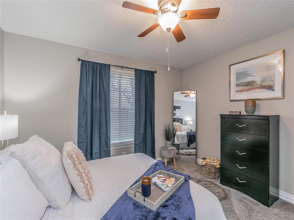 Bedroom with carpet flooring and ceiling fan at Riata Park Apartments