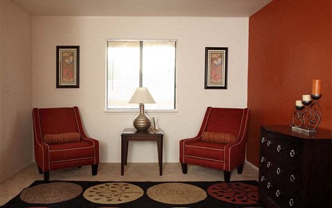 a living room with two red chairs and a table