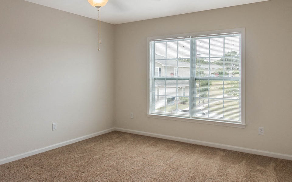 a living room with a large window and carpet