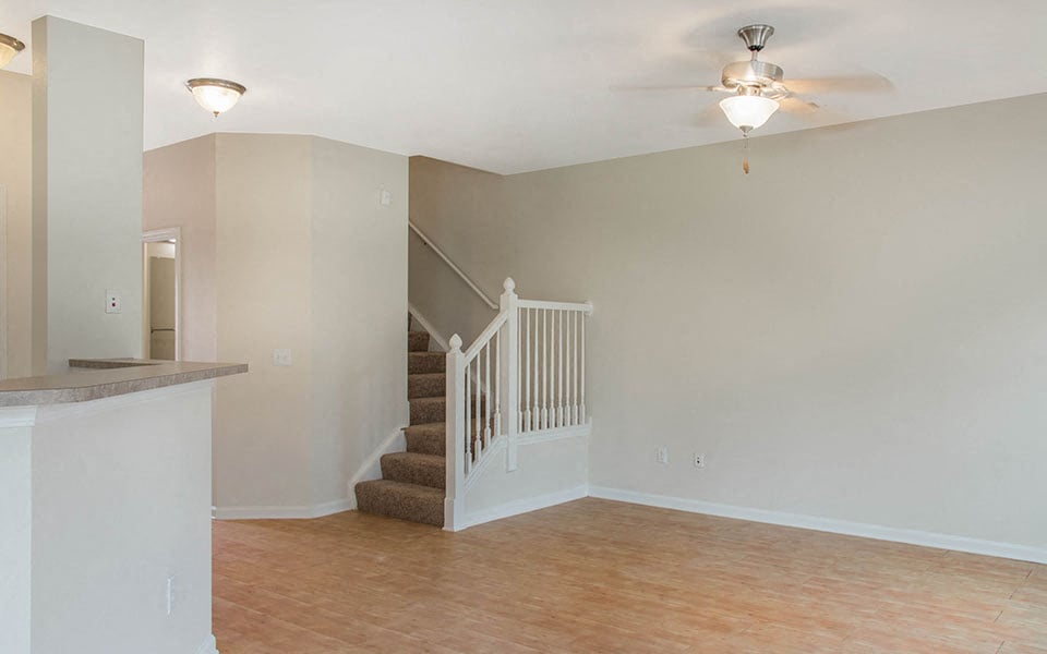 a living room with a staircase and a ceiling fan