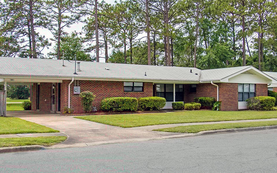 the front of a brick house with a driveway and lawn