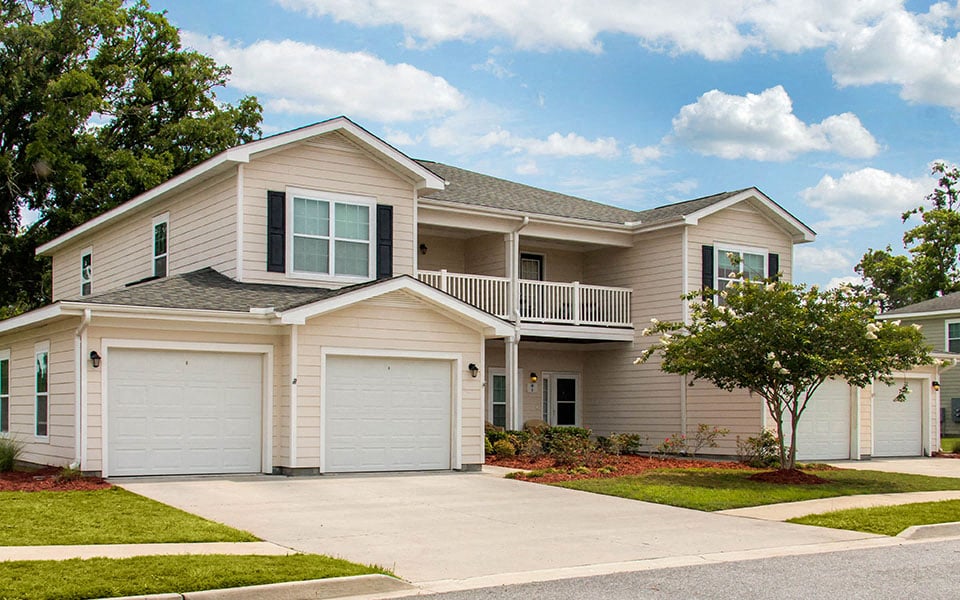 a beige house with two garage doors and a porch