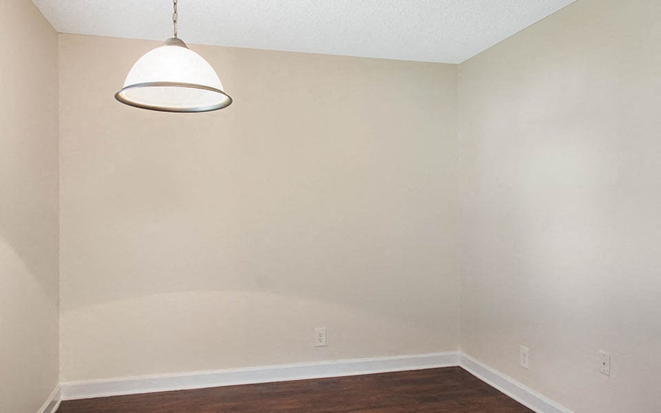 an empty room with a lamp on the wall and a wooden floor